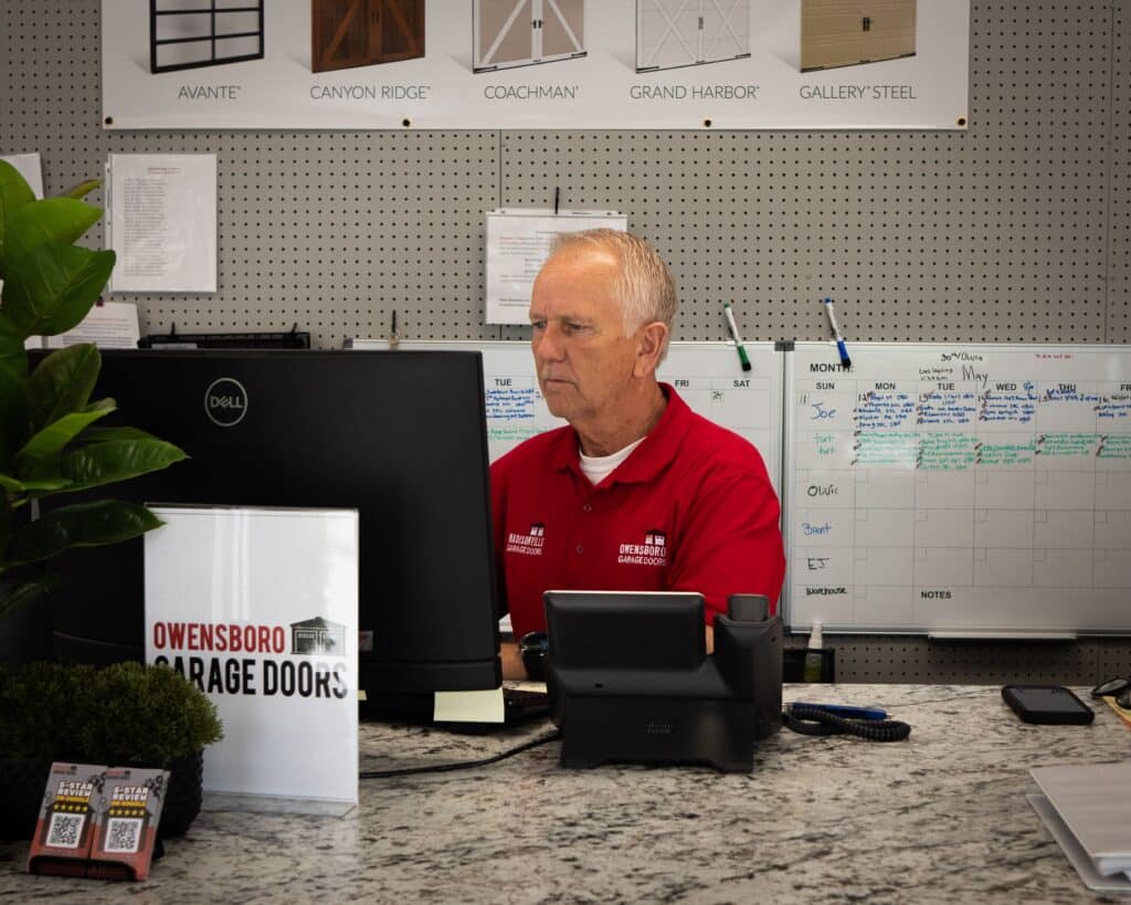 Les Deatherage, Scheduling & Service Manager behind the computer in an office location
